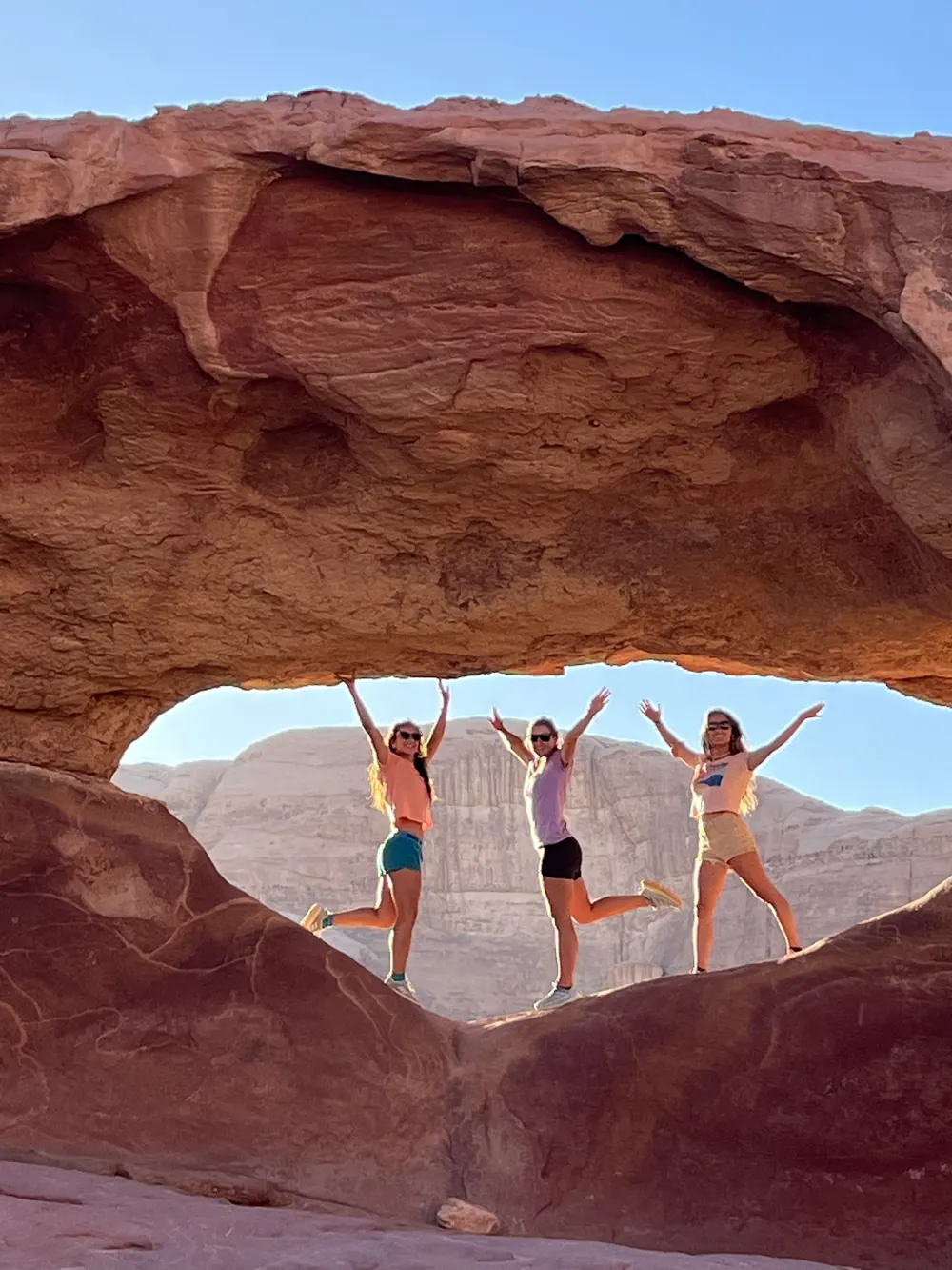 Travellers under a sandstone arch in Wadi Rum